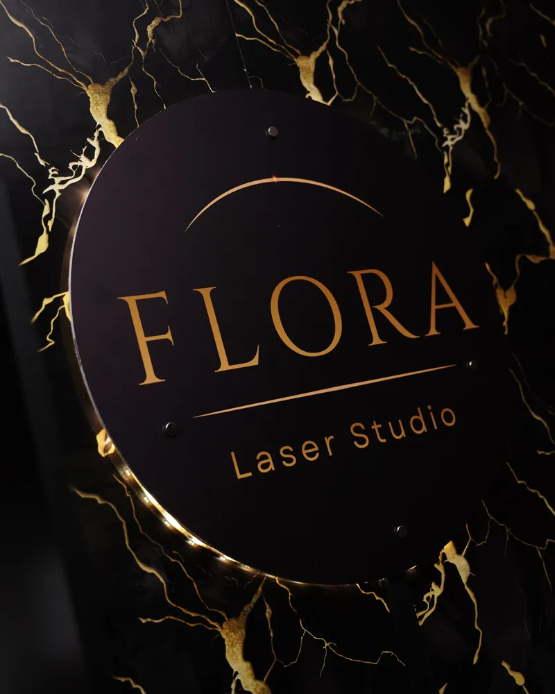 Podświetlony szyld FLORA Laser Studio na czarnym marmurze